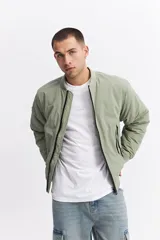Campera tipo bomber de nylon color verde oliva, con cierre frontal, cuello, puños y cintura elastizados.