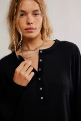 Top de tela con textura tipo gofrado, color negro, con escote redondo, botonadura henley y mangas largas abullonadas con puño.