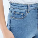 Pantalón jean de corte super skinny, tiro alto con cierre frontal de botones expuestos, confeccionado en denim elástico de color azul medio.