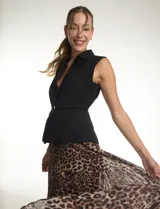 Vestido midi de estilo sastre con cuerpo tipo chaleco negro de cuello solapa y escote en V, con cierre lateral y cinturón con hebilla. La falda es plisada con estampado animal print y cuenta con forro interno.