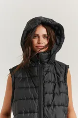 Chaleco negro oversize con capucha forrada en tela gamuzada, cierre metálico YKK, bolsillos laterales y tancas regulables en el ruedo.
