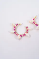 Aros tipo argolla decorados con cuentas de colores fucsia y rosa, intercaladas con pequeñas caracolas naturales y detalles metálicos dorados.