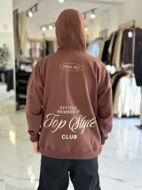 Canguro oversize de color marrón, con capucha y estampa en la espalda con el texto "Official Member of Top Style Club".