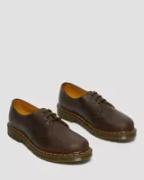 Zapato de tres ojales Dr. Martens modelo 1461, confeccionado en cuero Crazy Horse de color marrón con acabado encerado. Presenta costuras amarillas visibles en el borde de la suela y suela de goma con cámara de aire.