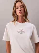 Remera boxy de algodón regenerativo en color blanco, con cuello redondo, manga corta y estampado gráfico con logo de Calvin Klein en el pecho.
