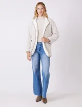 Cardigan beige con diseño de espiga, forrado en corderito sintético blanco. Presenta vivos en contraste color tostado en los bordes, cuello solapa y bolsillos tipo parche con solapa. Cierre frontal con botones carey.