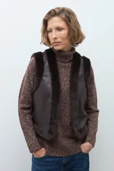Chaleco reversible de corte recto, con un lado de cuero sintético color chocolate y el otro lado de piel sintética al tono. Presenta cuello redondo y diseño sin mangas.