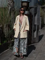 Blazer color crema de corte recto, con cuello de solapa, mangas largas y bolsillos laterales.