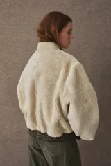 Campera tipo bomber de textura afelpada en color negro, con cierre frontal, cuello alto y puños y ruedo elásticos en cuero.