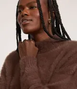 Suéter de punto color crema con cuello redondo y mangas largas ajustadas. Modelo slim alargado con efecto de pelitos.