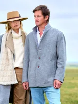 Saco de paño de lana en color gris, con cuello alto, cierre frontal de botones y bolsillos laterales.