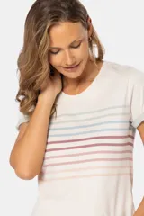 Remera de manga corta con cuello redondo, color base crema, con rayas horizontales en tonos pastel como rosado, azul claro y verde pálido. Los puños de las mangas son doblados y tienen un borde de color celeste pálido.