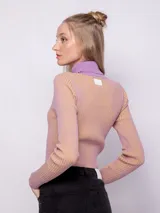 Polera de punto a rayas verticales en tonos gris plata y negro, de cuello alto y manga larga.