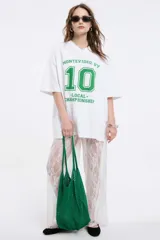 Remera oversize gris oscuro con cuello en V y mangas cortas. Presenta una estampa frontal estilo universitario con el número "09" y las inscripciones "MVD", "UY" y "PIMENTÓN ACTIVE" en tonos celestes y blancos.