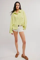 Blusa de lino color blanco crudo, de corte relajado, con cuello clásico, cierre frontal de botones, bolsillo en el pecho y mangas largas con presillas para arremangar.