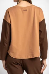 Sweater de algodón con diseño bicolor, cuerpo en color crema y mangas largas en color marrón oscuro. Presenta cuello redondo y un corte holgado tipo oversize.