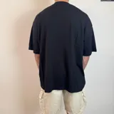Remera negra de corte oversize con cuello redondo alto y estampado gráfico de un sol con el texto MIDWY STUDIO en el centro del pecho.