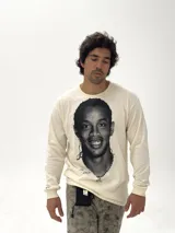 Remera de manga larga color beige con estampado fotográfico frontal de Ronaldinho en blanco y negro. Presenta un corte oversize y cuello redondo.
