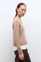 Sweater azul marino de manga larga con cuello redondo, combinado con una camisa celeste que se asoma por debajo.