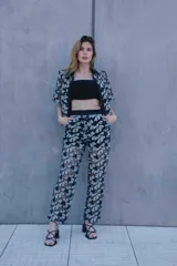 Conjunto de tres piezas compuesto por camisa de manga corta, pantalón de corte recto y top tipo bandeau. Todas las prendas presentan un diseño de encaje con estampado floral en blanco y negro.