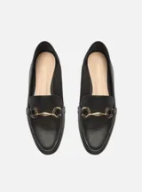 Mocasín de cuero negro con detalle de hebilla dorada.