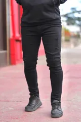 Pantalón chupín de jean color negro con roturas en las rodillas.
