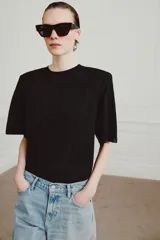 Camiseta de cuello redondo y manga corta con hombreras integradas. Presenta un corte regular fit con bajo recto y tejido fluido de lyocell.
