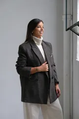 Blazer de corte sastrero en color gris oscuro con textura jaspeada. Presenta solapas clásicas, cierre frontal de doble botonadura y un bolsillo superior con detalle de pañuelo decorativo.