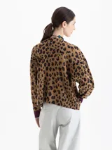 Sweater de punto con diseño animal print, cuello redondo y mangas largas con puños en contraste. Presenta un estampado central de cerezas y detalles bordados.
