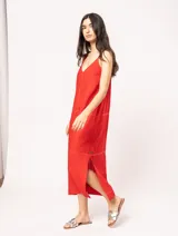 Vestido largo color crudo de lino, con silueta recta, escote en V, breteles anchos, detalle de elástico en la espalda y tajos laterales.