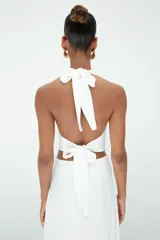 Top blanco de cuello halter con escote drapeado y espalda descubierta, confeccionado en tela de alta calidad con caída fluida.