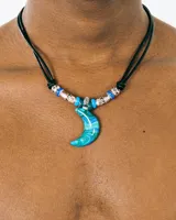 Collar de cordón negro ajustable con dije central en forma de luna de cristal con vetas azules y verdes, decorado con cuentas metálicas y de resina en tonos azules.