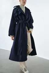 Trench oversize de Zara Woman Collection, color azul marino, confeccionado en hilatura con mezcla de algodón. Presenta cuello solapa, manga larga ajustable con trabillas, bolsillos delanteros y cinturón del mismo tejido con lazadas. Destacan los pespuntes marcados a tono y el cierre frontal cruzado con botones.