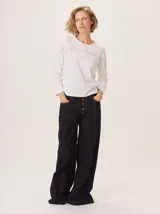 Pantalon ancho de denim en varios tonos de azul con diseño patchwork, de tiro medio y cierre frontal con botones.
