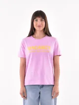 Remera rosa de manga corta con cuello redondo y estampado frontal en amarillo que dice "VACANCY" y "POOLSIDE VIEWS AVAILABLE".