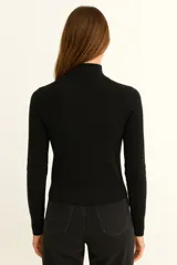 Polera de tejido acanalado color beige, con cuello alto y detalle de botones decorativos en el hombro. De corte ajustado al cuerpo y manga larga.