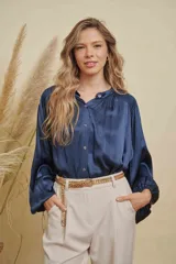 Blusa de satén color azul marino, con cuello mao, cierre frontal de botones y mangas largas con puños elásticos. Presenta detalles fruncidos en los hombros.