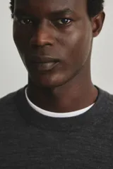 Buzo de punto fino confeccionado en lana merino, color gris oscuro. Presenta cuello redondo, mangas largas y terminaciones acanaladas en cuello, puños y bajo. Posee un corte regular fit para una silueta clásica.