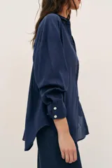 Camisa de corte amplio confeccionada en algodón, con cuello solapa, manga larga, bolsillo delantero de plastrón y cierre frontal con botones.