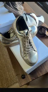 Zapatillas de cuero color dorado con acabado metalizado, cordones al tono y suela de goma color suela.