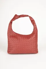 Cartera marrón de símil cuero trenzado con asa fija anudada. Cuenta con tres bolsillos interiores.