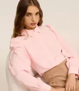 Camisa celeste de crepé con cuello inglés, manga larga abullonada y abotonadura frontal.