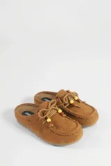 Mocasín destalonado de gamuza color marrón, con diseño tipo zueco, costuras pespunteadas en el empeine, cordones frontales decorados con cuentas y suela plana de goma.