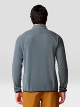 Buzo polar Mountain Hardwear modelo Microchill 1/4 Zip, color gris, con cuello alto, cierre frontal parcial de un cuarto y mangas raglán. Presenta detalles en color negro en los bordes del cuello, puños y ruedo, además de un pequeño logo bordado en el pecho.