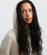Buzo oversized de corte holgado, color negro, con capucha ajustable mediante lazos, mangas largas y puños elásticos.