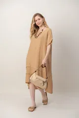 Vestido midi de lino color beige, de corte holgado, con mangas cortas amplias, cuello redondo y detalle de tablas en la falda con bolsillos.