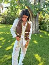 Chaleco de sastrería con estampado de manchas tipo cowhide, cierre frontal con botones y detalles de pasamanería en cuero rojo en los bordes y bolsillos. Presenta un diseño clásico con espalda en lino.