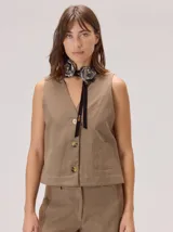 Chaleco de corte recto y estilo sastrero, color beige, con escote en V, cierre frontal con botones y un bolsillo lateral aplicado.