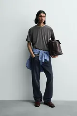 Camiseta relaxed fit color gris oscuro, confeccionada en tejido ligero de algodón con elasticidad. Presenta cuello redondo y manga ranglán corta.