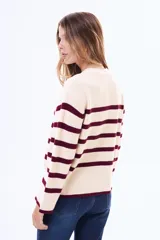Buzo tejido de punto con diseño a rayas horizontales en color crema y bordó, de cuello redondo y mangas anchas.
